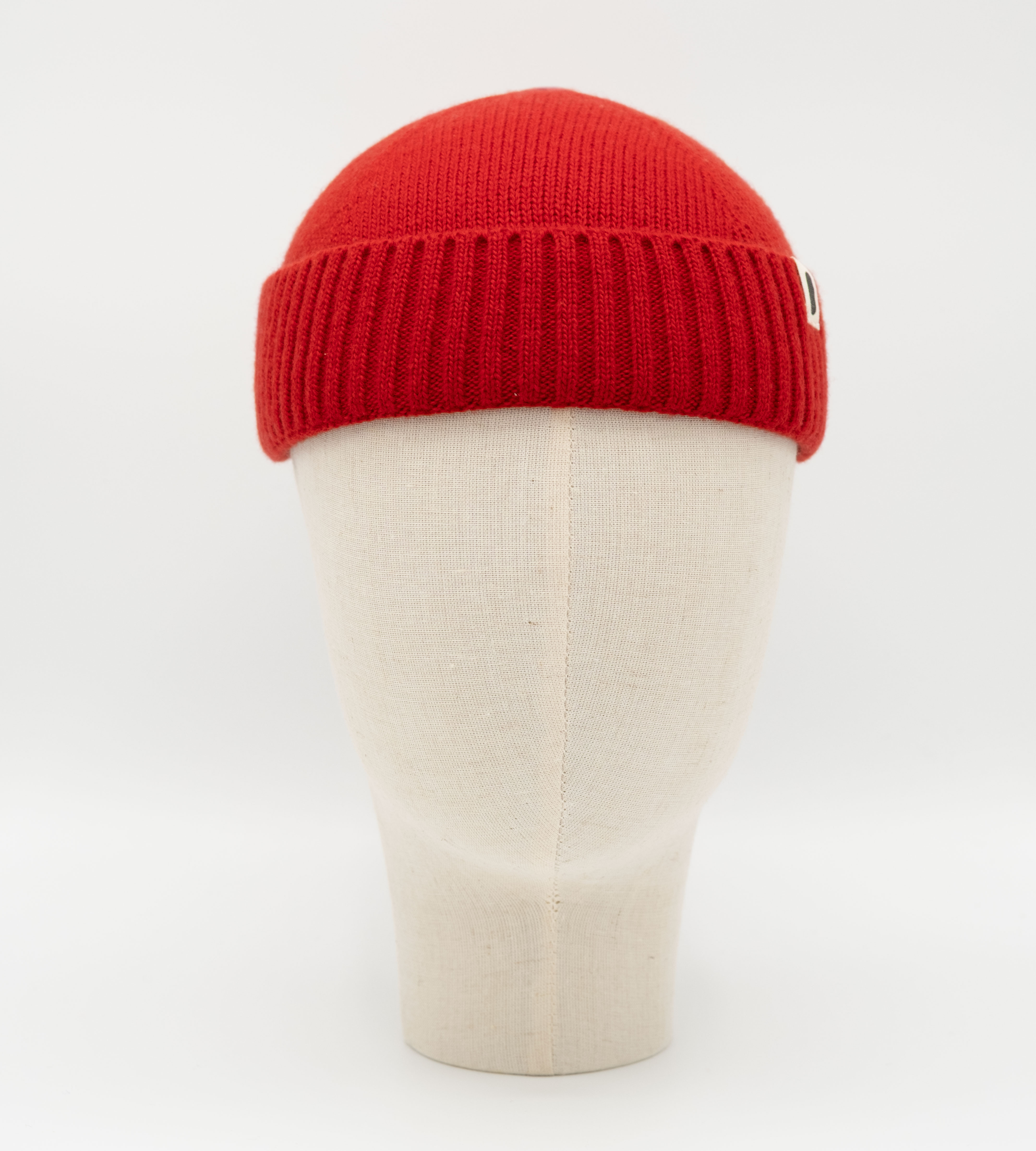 Rote Strickmütze mit Rippbund auf einer Leinenkopfform