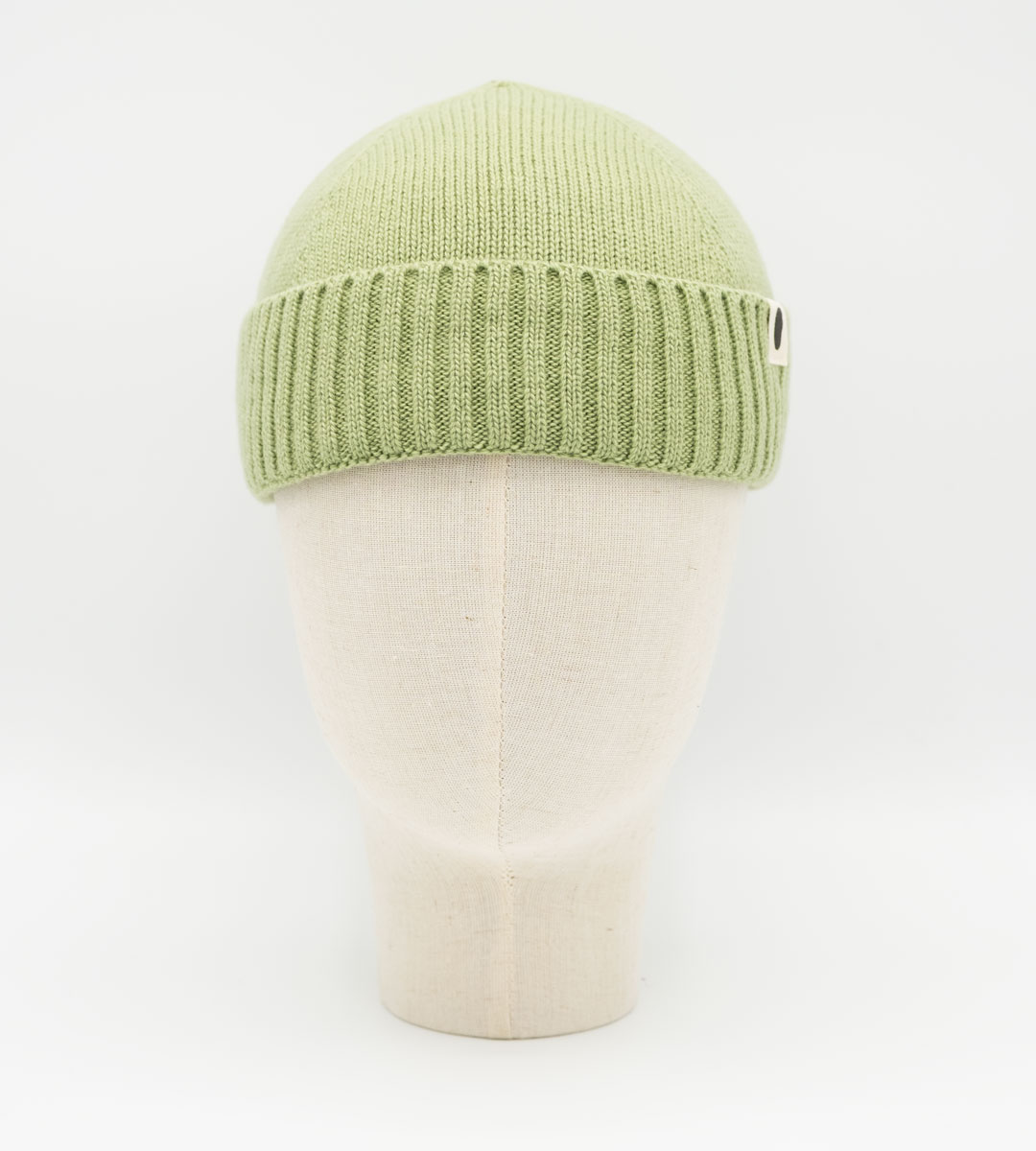 Hellgrüne Strickmütze mit Rippbund auf einer Schaufensterkopfform