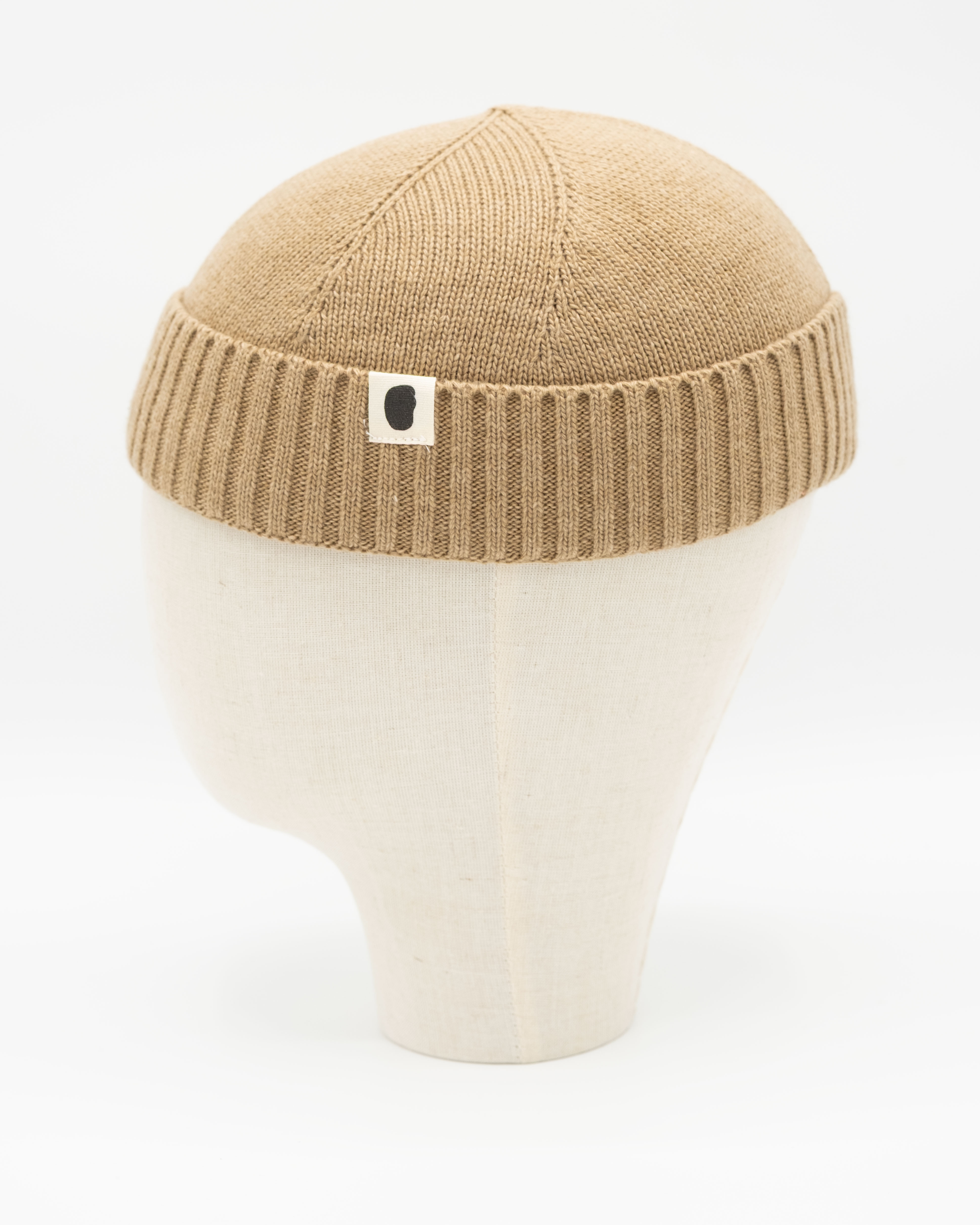 Beigefarbene gestrickte Docker-Mütze auf weißem Mannequin-Kopf