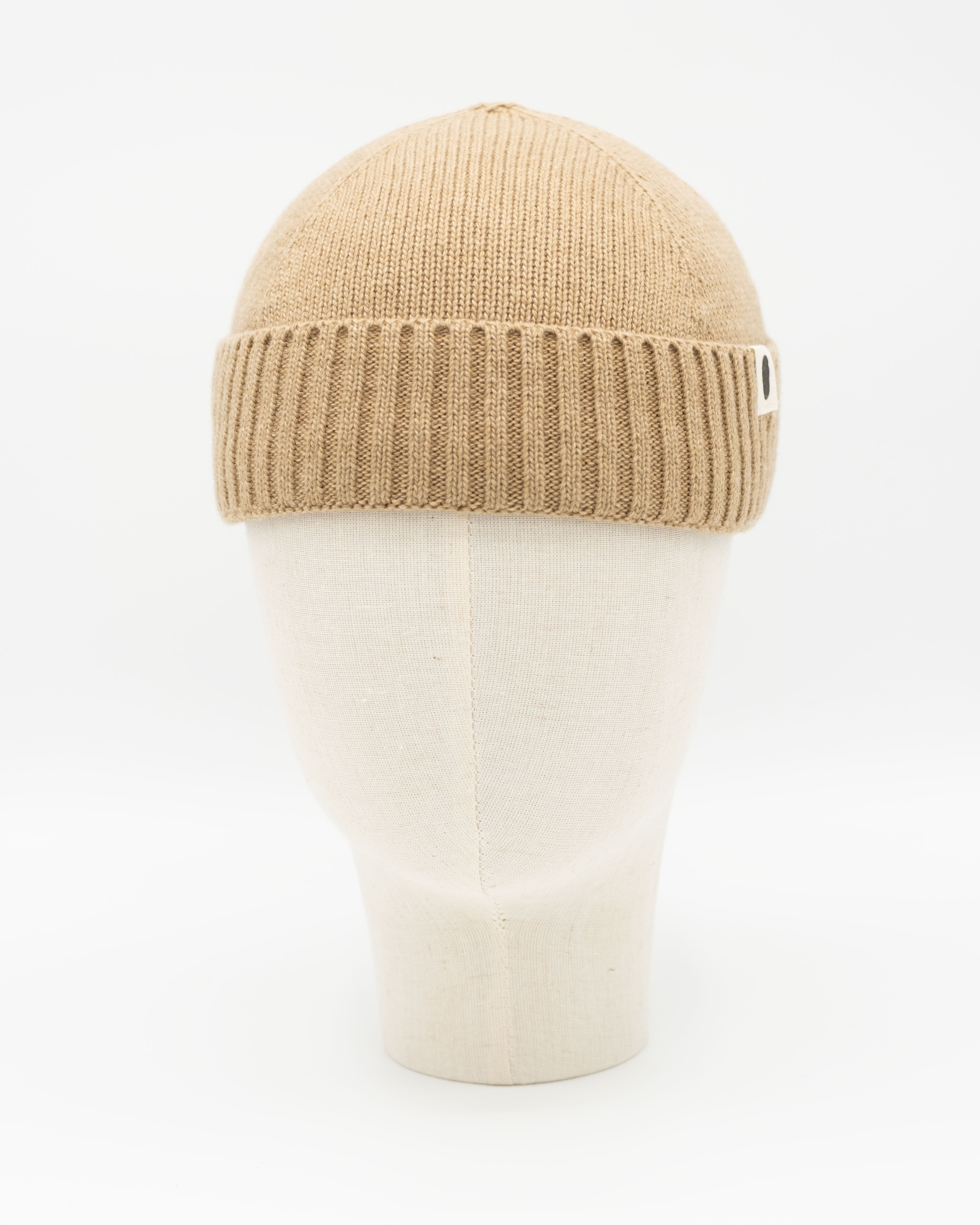 Beigefarbene Strickmütze mit Rippbund auf weißem Mannequinkopf