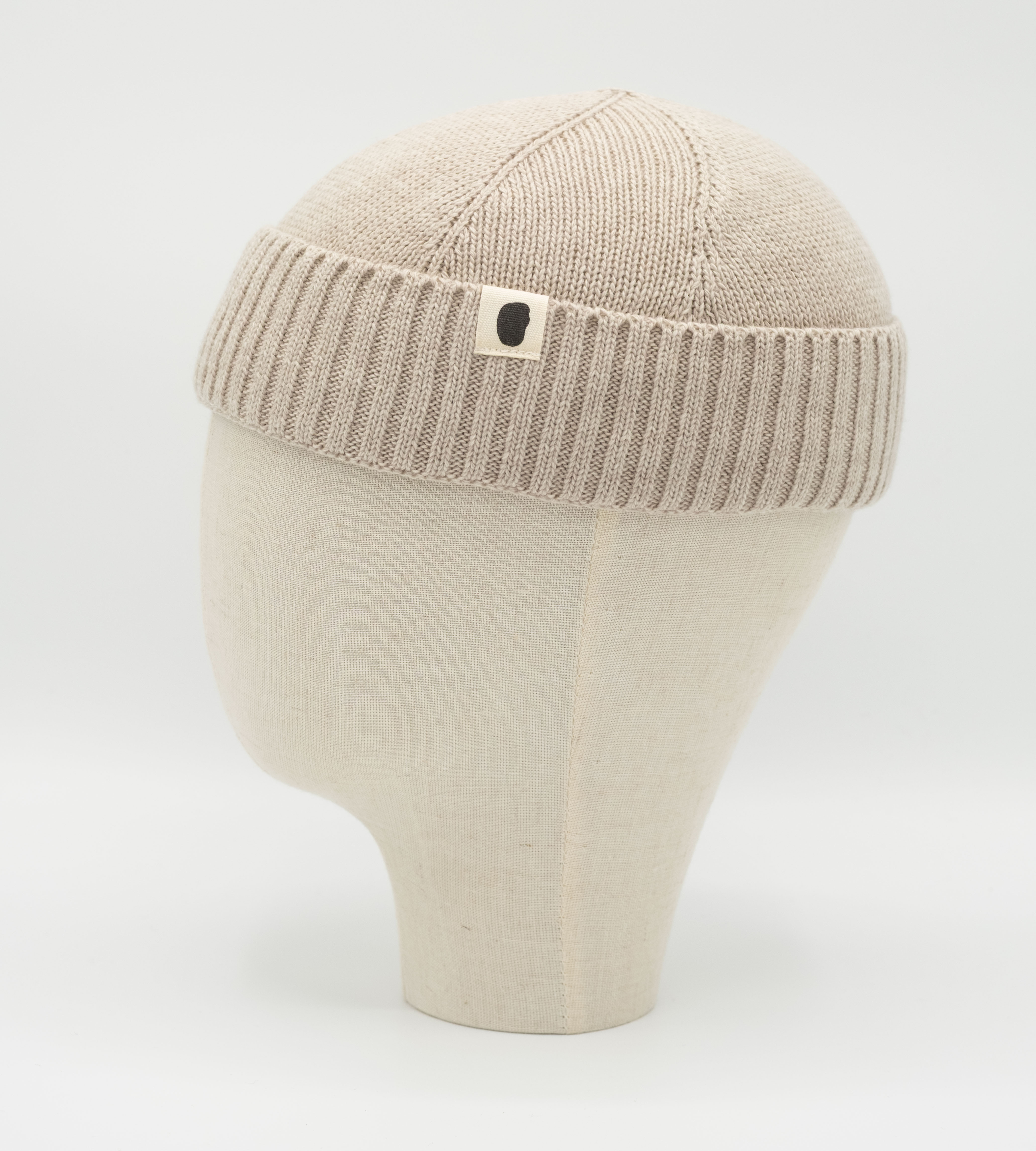 Beigefarbene Strickmütze aus Wolle auf einem Mannequin-Kopf