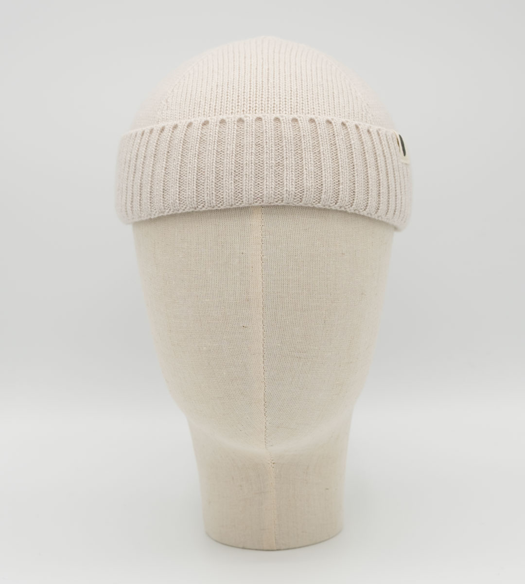 Cremefarbene Strickmütze mit Rippbund auf einer Schaufensterkopf-Büste