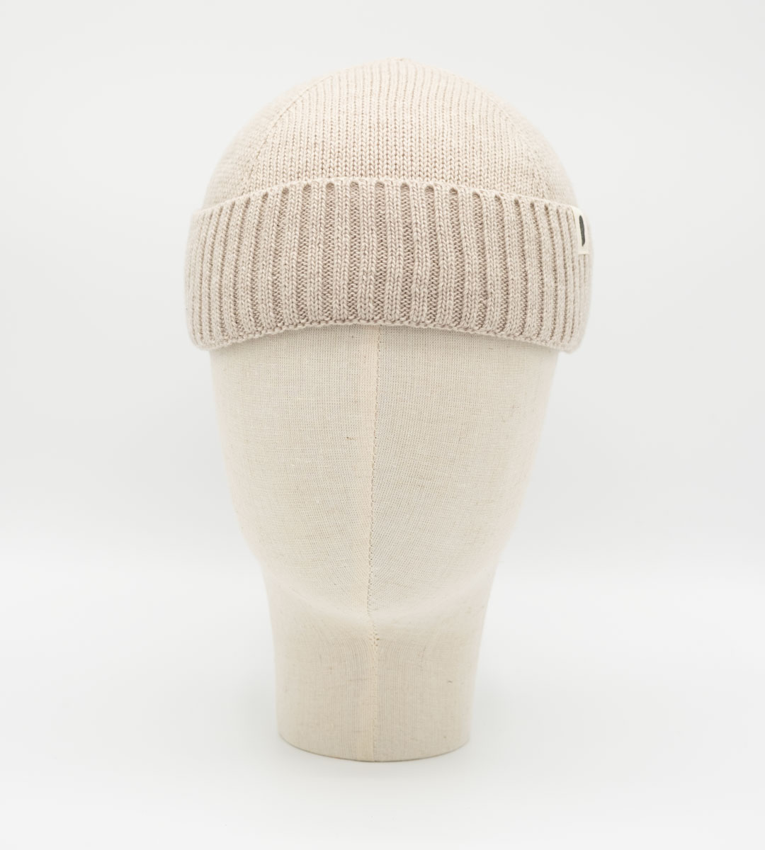 Beigefarbene Strickmütze mit Rippbund auf einem Mannequinkopf