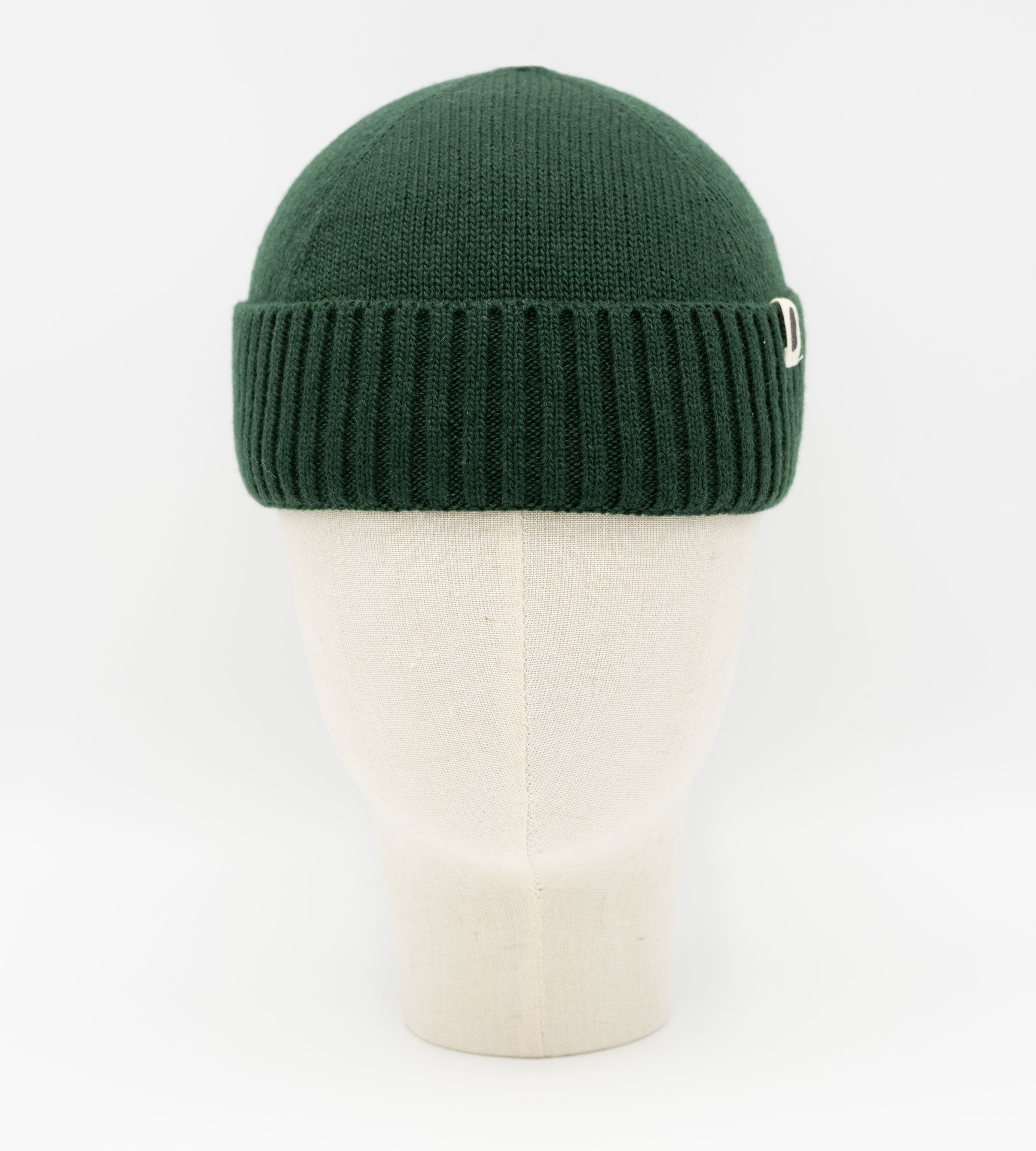 Dunkelgrüne gerippte Strickmütze mit Umschlag auf einer Büste