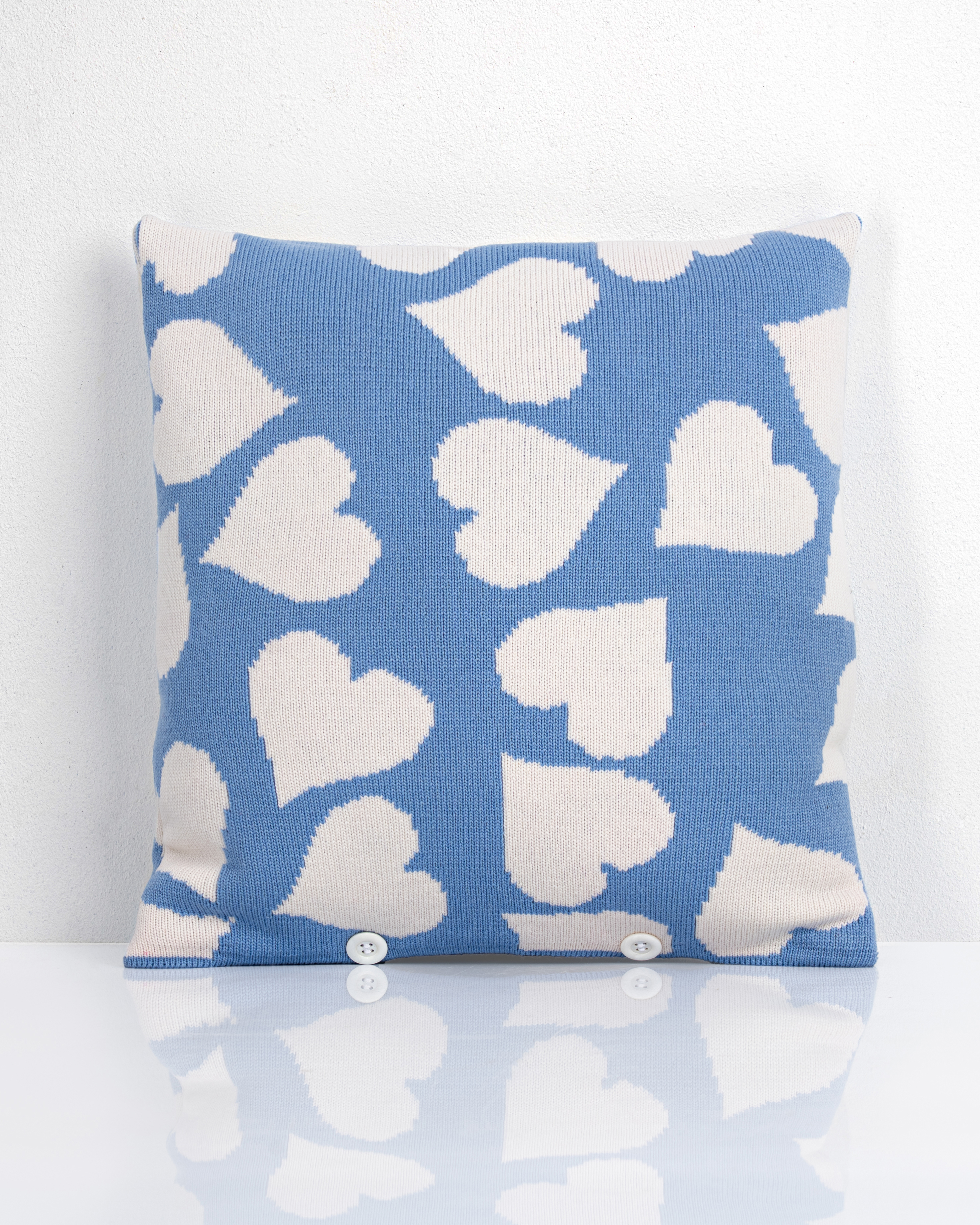 Gestricktes Kissen in Blau mit weißem Herzmuster und Knopfleiste