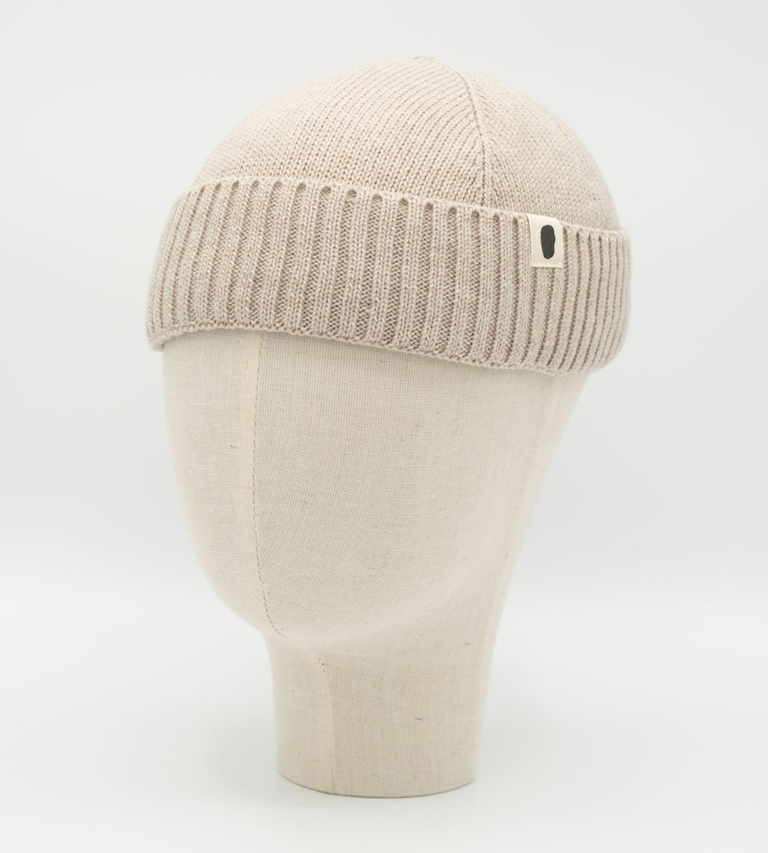 Beigefarbene Strickmütze mit Rippbund auf einer Schaufensterkopf-Büste